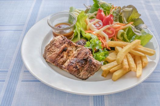Grilled steak with french fries and fresh vegetables on white plate