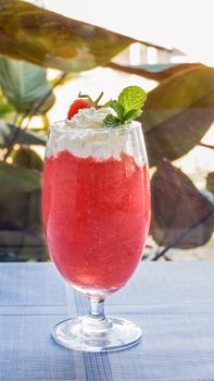 Fresh strawberry smoothie with whipping cream in a glass on the table