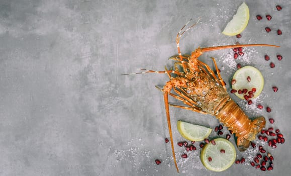 Top view of steamed lobster with lemon and pomegranate  on cement background