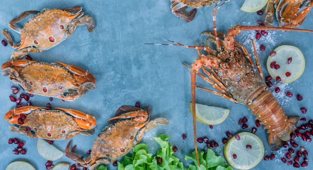 Food frame with crustacean . Lobster, crab, lemon and  pomegranate on background