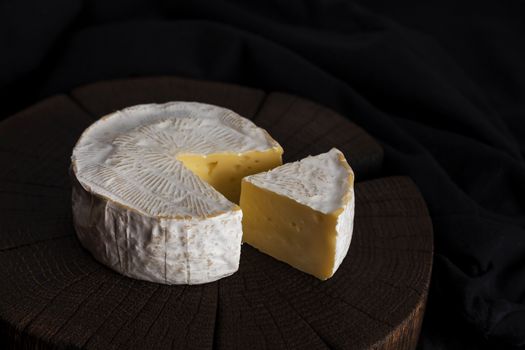 Camembert cheese on black wooden background, copy space