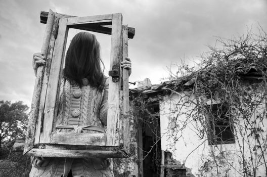 Horror Scene of a scary girl over a spooky abandoned house background