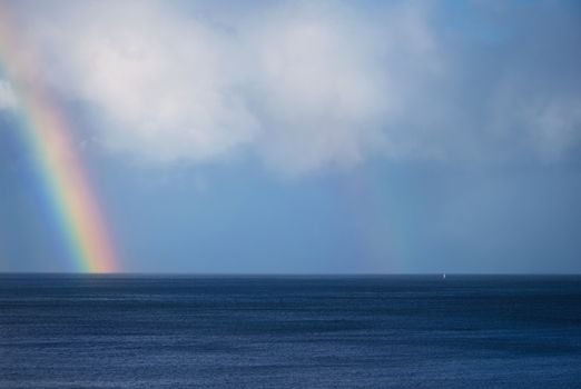 Beautiful rainbow and boat on the ocean horizon