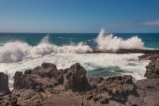 Unidentifiable Tourist swimming in coastline landscape in Puerto Santiago, Tenerife, Spain.