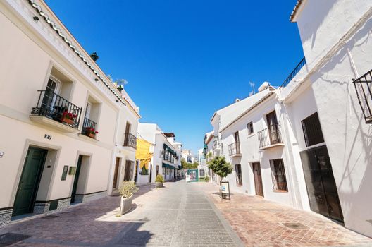 Typical street with white houses in the touristic village of Nerja, Malaga, Spain.