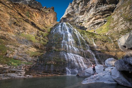 Hikker womann looking at Horsetail waterfall in Ordesa national park, Pyrenees, Spain.