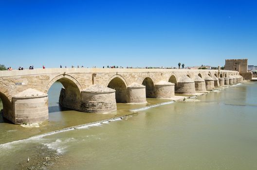 Roman bridge and Guadalquivir river over blue bright sky in Cordoba, Andalusia, Spain.