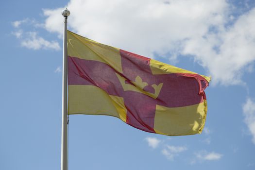 The Flag of the Swedish Church with a partly cloudy sky.
