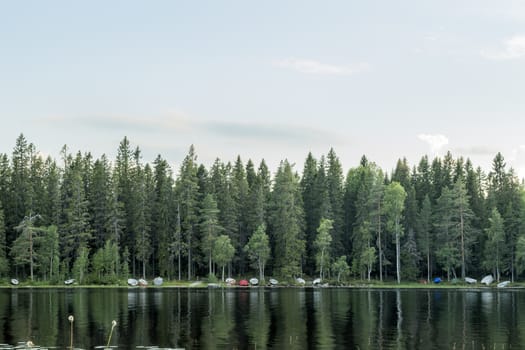 Rowboats by Lake with forest and sky.