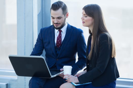 Business people having a break, sitting with laptop and smiling