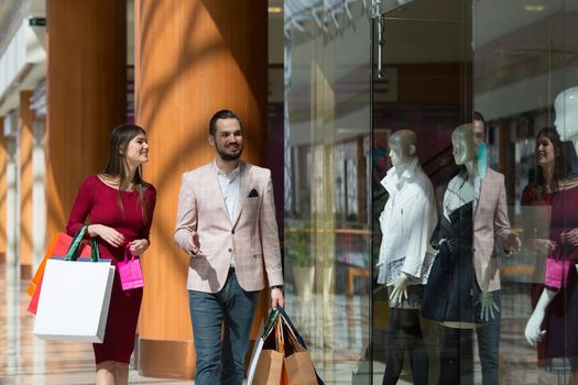 Happy beautiful young couple with shopping bags in mall