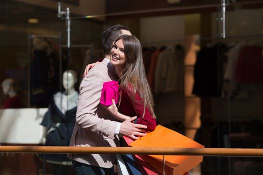 Happy beautiful young couple with gift bag hug in shopping mall