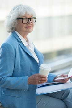 Senior business woman at coffee break with documents