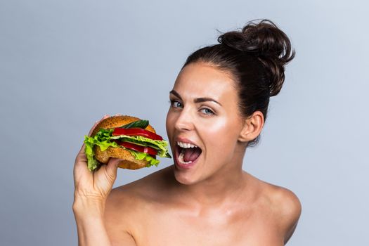 Young woman eating burger made of fruits and vegetables, healthy eating concept