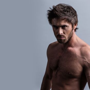 Dark shot of healthy muscular naked young man on gray background