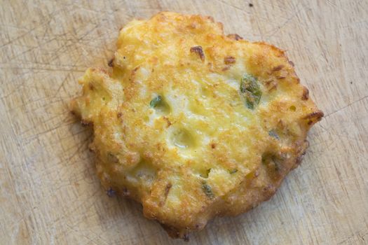 fried zucchini fritter on wooden background