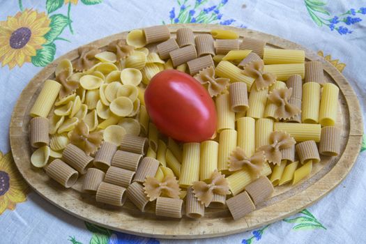  assorted wholemeal and normal raw pasta with a fresh tomato