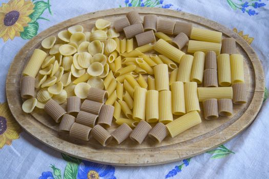 raw assorted wholemeal and normal pasta on a wooden dish