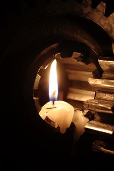 Lighting candles between old gears against dark background
