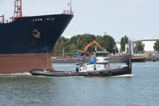 small tug boat relase the cables after pulling the big ship trough the maas river in Holland
