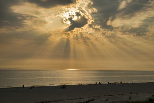 people at the beach during sunset in the hottest summer in holland ever, the beach is near europoort with the ships at the horizon