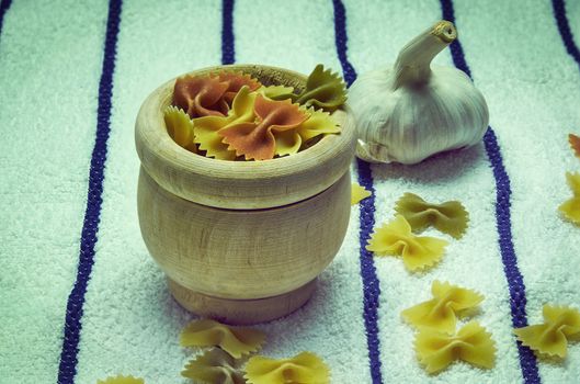 Wooden mortar filled with Italian pasta with garlic ingredients for preparation