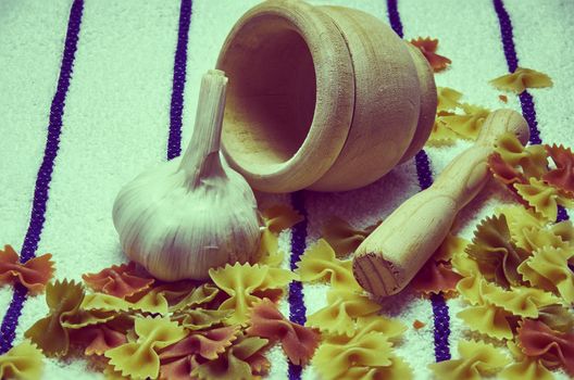 Wooden mortar filled with Italian pasta with garlic ingredients for preparation