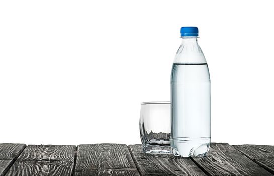 Empty glass and bottle of water. Plastic bottle on a wooden table. Isolated on white background.