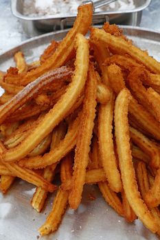Heap of sweet fresh churros, traditional Spanish or Portuguese deep fried dough pastry snack cooked close up, high angle view
