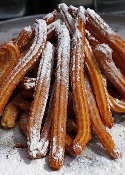 Heap of sweet fresh churros with sugar, traditional Spanish or Portuguese deep fried dough pastry snack cooked close up, high angle view