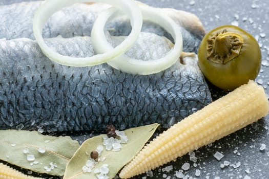 Saltwater marinated fish, cold appetizer. Herring fillet marinated on black cutting board
