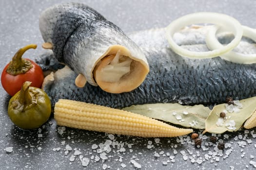 Saltwater marinated fish, cold appetizer. Herring fillet marinated on black cutting board