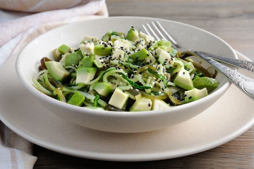 Salad from noodles from cucumbers and laminaria, slices of avocado with sesame