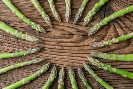 Raw garden asparagus stems. Fresh green spring vegetables on wooden background. (Asparagus officinalis).