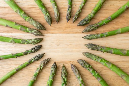 Raw garden asparagus stems. Fresh green spring vegetables on wooden background. (Asparagus officinalis).