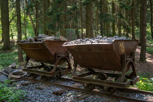 Mining cart with stones. Old and abandoned mining cart in forest.
