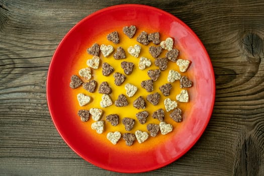 Plate with heart shaped cookies on wooden table