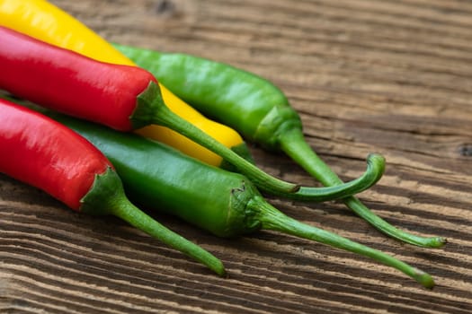 Spicy chilies peppers on wooden background. Colorful peppers on rustic wooden table. Raw healthy food.