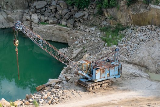 Mining in the granite quarry. Working mining machine - old crane. Mining industry.