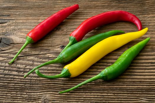 Spicy chilies peppers on wooden background. Colorful peppers on rustic wooden table. Raw healthy food.