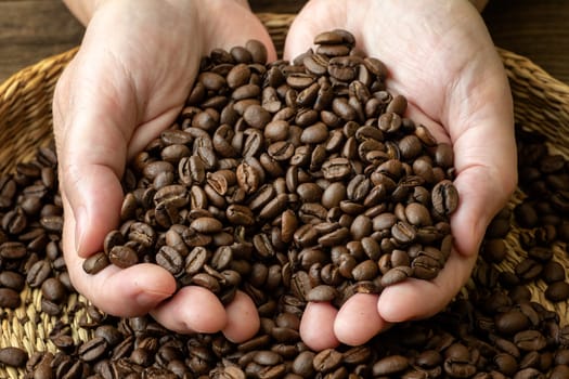 Coffee beans in female hands. Female hands with roasted coffee beans.