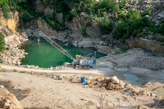 Mining in the granite quarry. Working mining machine - old crane. Mining industry.