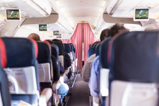 Interior of commercial airplane with passengers on seats during flight. The curtain separates economy from business class.