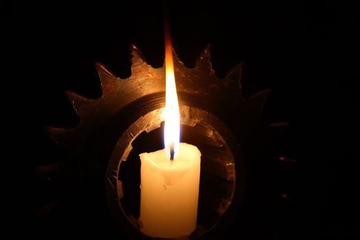 Abstract composition with lighting candle inside old gear