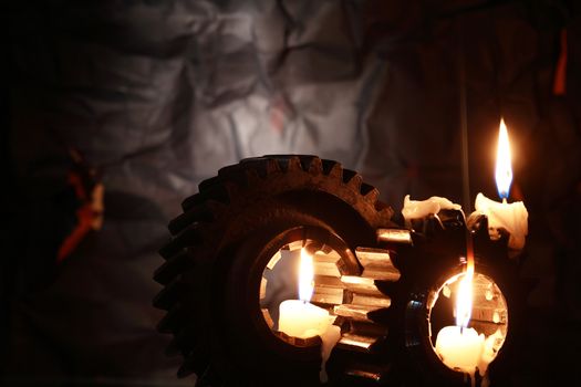 Lighting candles between old gears against dark background