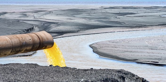 The industrial wastewater is discharged from the pipe into the water.