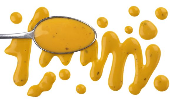 Honey mustard sauce. Splashes and spilled salad dressing isolated on white background with clipping path.