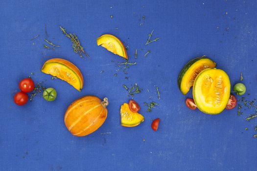 Food concept background. Pumpkin, tomatoes and thyme on a blue table. Top view