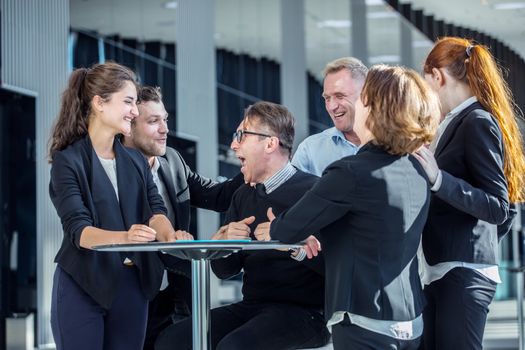 Group of happy business people congratulating their successful coworker