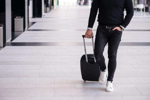 Man walking with wheeled bag at airport terminal and talking on phone